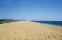 The shingle beach and lagoon stretching towards distant horizon with sunbathers along the shoreline.