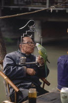 Man sitting at cafe table holding a parrot