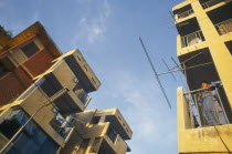 New housing estate. View looking up at buildings with boy standing on a balcony