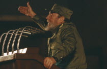 Fidel Castro in military uniform making a speech from a podium