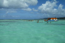 The Nylon Pool with tourists swimming or standing in shallow water by boat