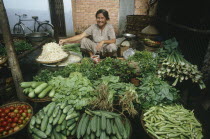 Smiling woman at her vegetable stall in a street market