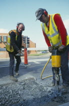 Workmen with pneumatic drill digging up the road
