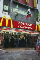 McDonalds fast food restaurant with customers and sign above written in Japanese