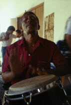 Man playing tall bongo type drum with his handsPercussion InstrumentDrumsCaribbean Cuban Trini Trinidadian West Indies Hispanic Latin America Latino Male Men Guy American Male Man Guy