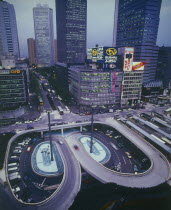 Shinjuku with aerial view onto road intersection at night with skyscrapers behind