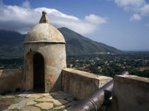 Santa Rosa Fort  corner of crenellated battlements with a cannon.  View towards mountains beyond.