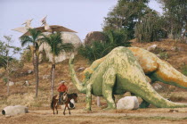 Parco Prehistorico dinosaur replicas with man on horseback riding past