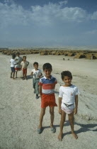 Group of Kurdish refugee children at Haji Camp with rows of tents behind them