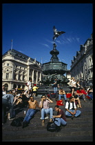 Picadilly Circus with people congregating on the steps surrounding the base of Alfred Gilberts Eros statue dating from 1892