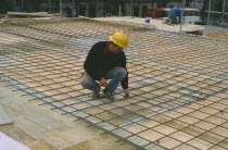 Workman laying reinforcing steel for flooring