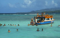 The Nylon Pool with tourists swimming or standing in shallow water by crowded glass bottom boat