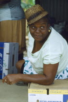 Female banana packer wearing hat and leaning on box