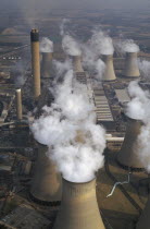 Aerial view over cluster of Power Station chimneys releasing white smoke into the atmosphere.