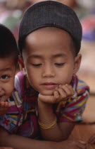 Burmese Karen refugee child in camp looking down with his chin in his hand