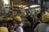 A traditional dagashiya penny candy store  selling masks and toys  with elementary student boys and girls in yellow school beretssweet shop