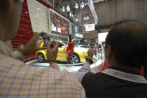 Tokyo Auto Show  men take pictures of a model with KIA SUV  man on right uses mobile phone to take picture  "otaku" behavior.Cell phoneCarAutomobile