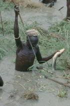 Dinka tribesman catching fish with barbed fishing spear.