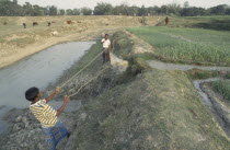 Men operating irrigation system incorporating manual swing basket.