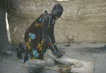 Shilluk woman grinding sorghum to make bread.