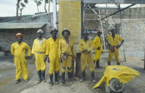 Group of miners in safety helmets and work clothes at Patchway gold mine with Code of Signals mining regulations notice behind them.