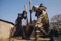 Women pounding maize  one carrying baby on her back.