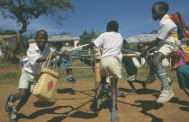 Primary school children playing on roundabout. Young boy smoking cigarette.