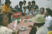 Large group of people having a meal of meat and rice.  Rice is a staple food and eaten at all meal times.