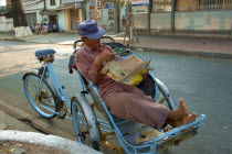 A Cyclo driver reading a magazine taking a break