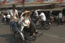 Two women riding a Cyclo on a busy street
