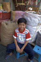 A young boy sitting next to sacks of dried herbs.Son of the owner of the Chinese herbal shop