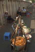 Sellers lined up against a wall selling food being from the street