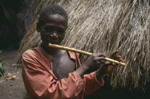 Young boy playing home made flute.