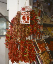 Via Genova  Main Street. Dried Chilli peppers hanging outside a shop. Sign says Natural Viagra.