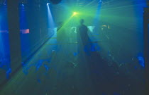 The Ministry of Sound night club. Two people on a platform above crowd of dancers. Blue and green lighting.