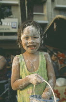 Young girl with bucket  covered in mud at the Songkhran Festival. Thai New Year  15 April.