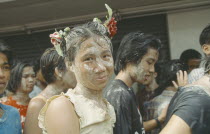 Crowd covered in mud  young girl with flowers in hair   celebrating the Songkhran Festival. Thai New Year  15 April.