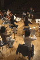 Conductor and music teacher leading dress rehearsal of junior and senior high school students in the United Freedom Orchestra for spring concert.  music teacher Satoshi Miyano  MR 13