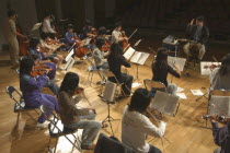 Conductor and music teacher leading junior and senior high school students in dress rehearsal for spring concert in the United Freedom Orchestra  Music teacher Satoshi Miyano  MR 13