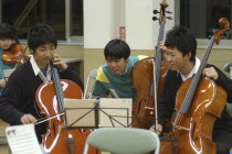 Three teenage male Cello players in the United Freedom Orchestra joke about music during a rehearsal break.left is Kazuto Sawawatari  17 years old  MR 4  center is Shyota Sawawatari  17 years old  M...