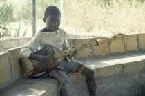 Boy with guitar made from oil can and piece of wood.recycled