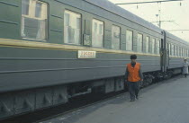 Trans Siberian train and guard at platform of station.