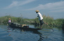 Fishing boat rowed by oarsman using one leg. Burma