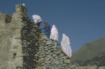 Women climbing stone footbridge.