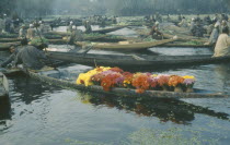 Early morning market on Dal Lake with wooden canoe full of flowers in the foreground.