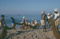 Fishermen on beach pulling in nets.Kerela Kovalum Kerala Kovalam