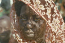 Portrait of Kanuri Arab woman with sun through head dress casting shadow patterns across her face.