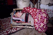Kazakh baby in crib inside kigizuy or yurt. Ger