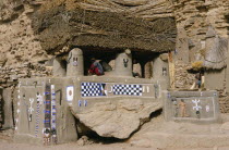 Newly painted Dogon Toguna or meeting place with men sitting on raised floor between pillars supporting thick millet thatched roof.case a palabres Togu Na