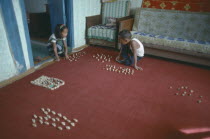 Domestic interior with children playing game using knuckle bones to create herds of animals.